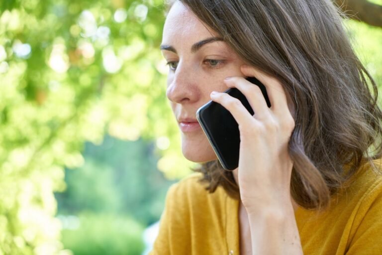 Woman holding smartphone on phone call outdoors - Record Android phone calls with RECAP