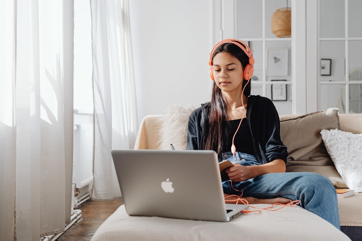 Young woman wearing headphones working on MacBook - Remove background noise in Audacity