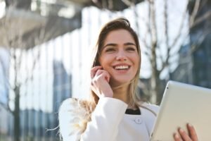 Smiling woman on phone call holding tablet outdoors - Record iPhone calls with RECAP