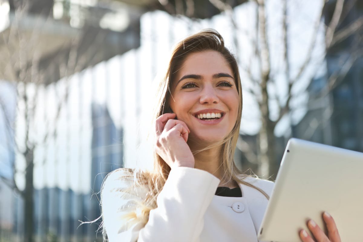 Smiling woman on phone call holding tablet outdoors - Record iPhone calls with RECAP